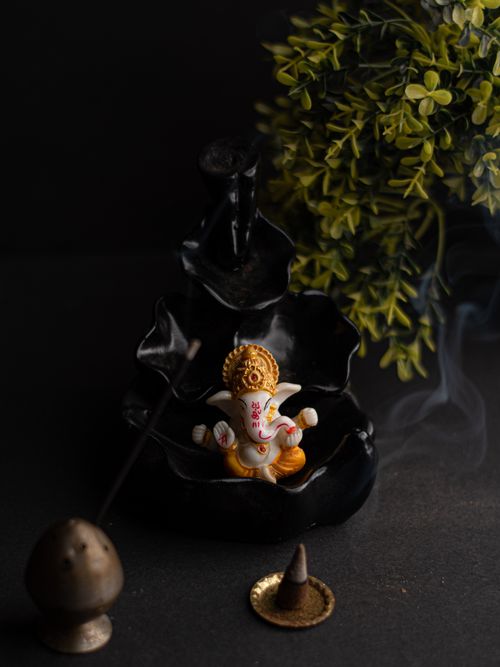 Free Ceramic Ganesha statue with incense and leaves in a calm setting. Stock Photo
