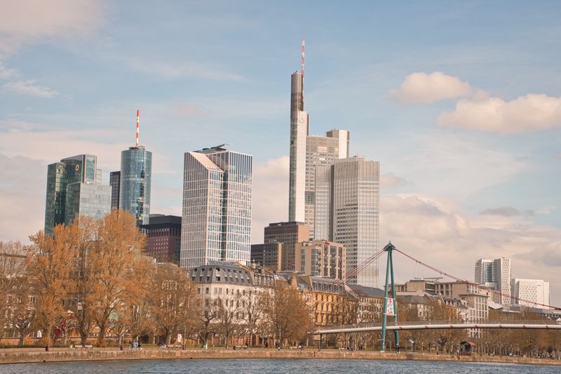 Skyline of Frankfurt am Main featuring skyscrapers and river during daytime.