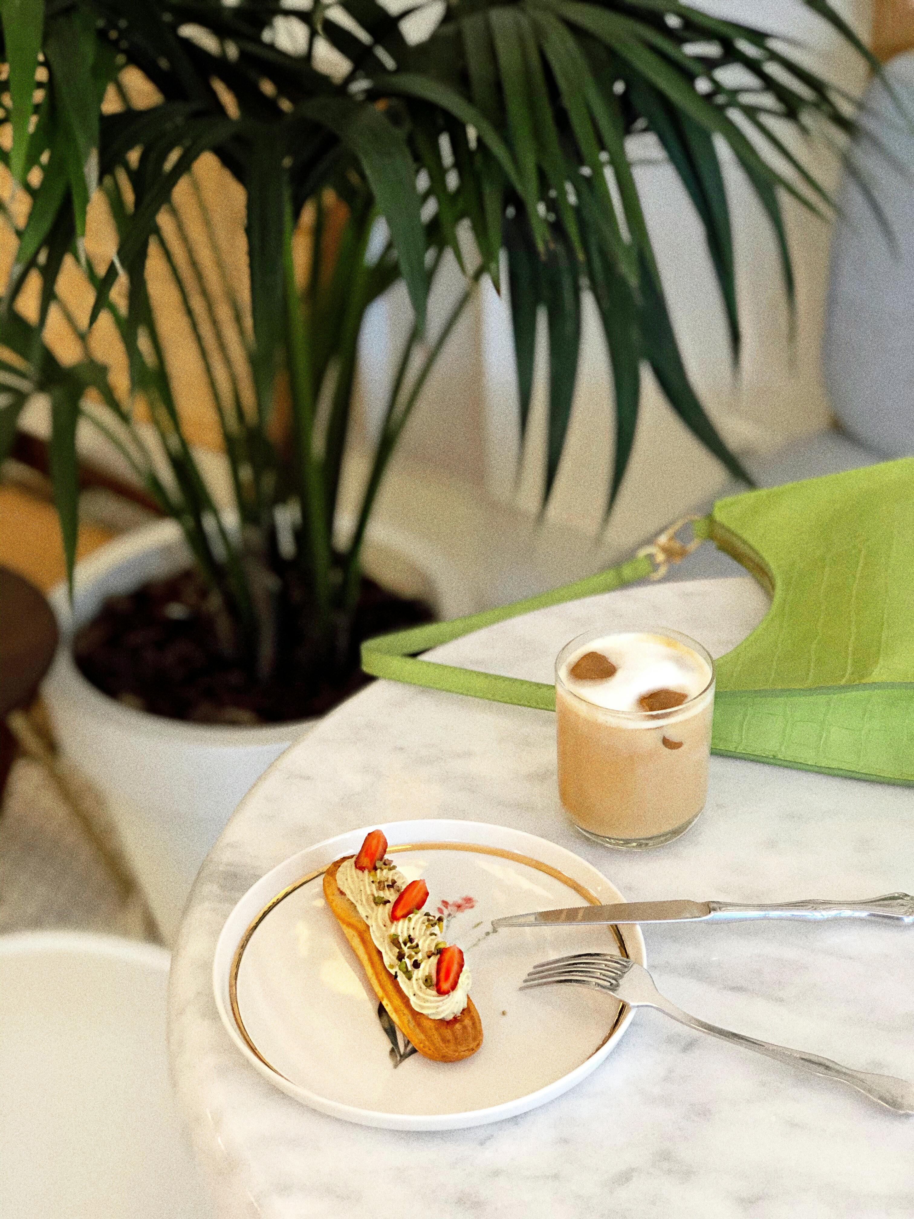 A tasty eclair and iced coffee elegantly presented on a marble table, perfect for a gourmet treat.