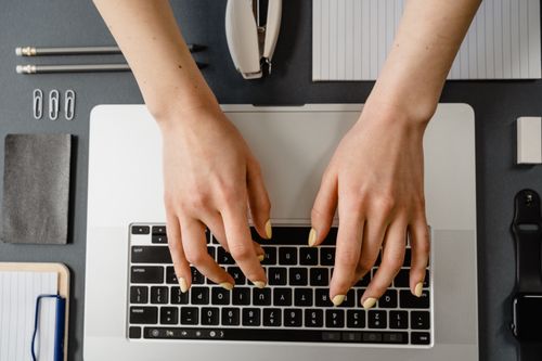 Free Close-up of woman's hands with manicured nails typing on a laptop. Stock Photo