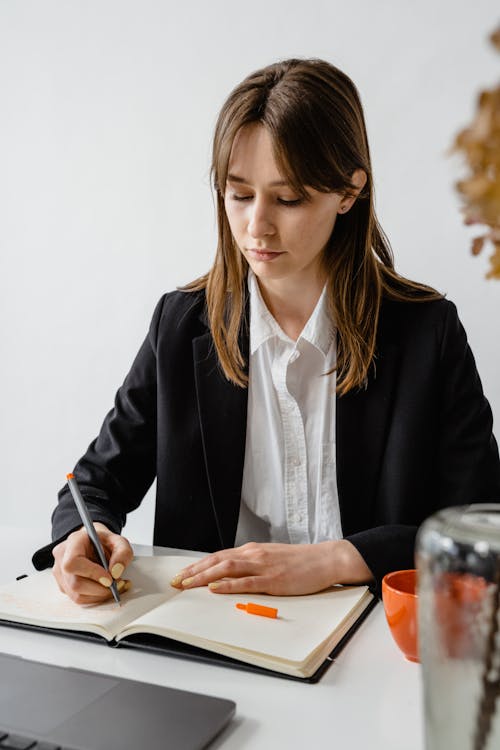 Free Photo of a Woman in a Black Blazer Writing With a Gray Pen Stock Photo