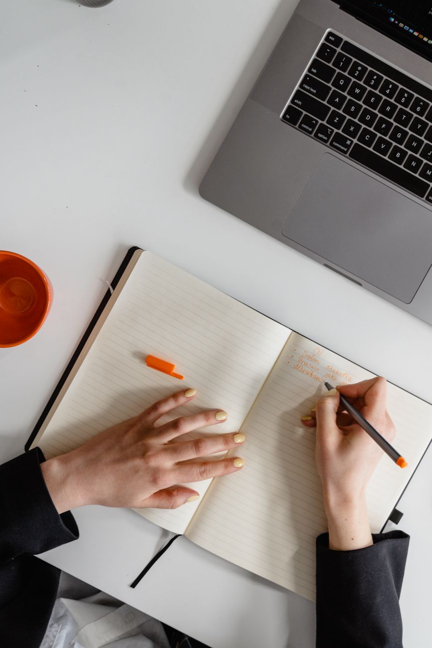 Personne qui prend des notes à côté d’un ordinateur portable