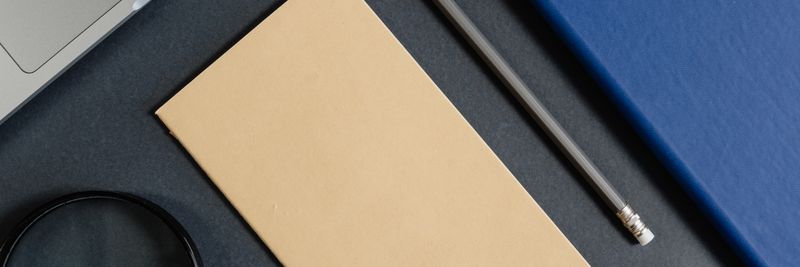 Flat lay of office stationery items with a minimalist design on a dark background.