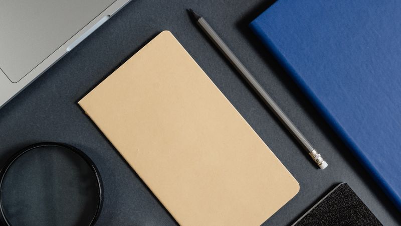 Flat lay of office stationery items with a minimalist design on a dark background.