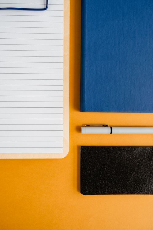 Free Flat lay of notepad, books, and pen on colorful background for office work. Stock Photo