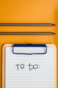 Top view of a clipboard with 'To Do' list and pencils on a vibrant yellow background.