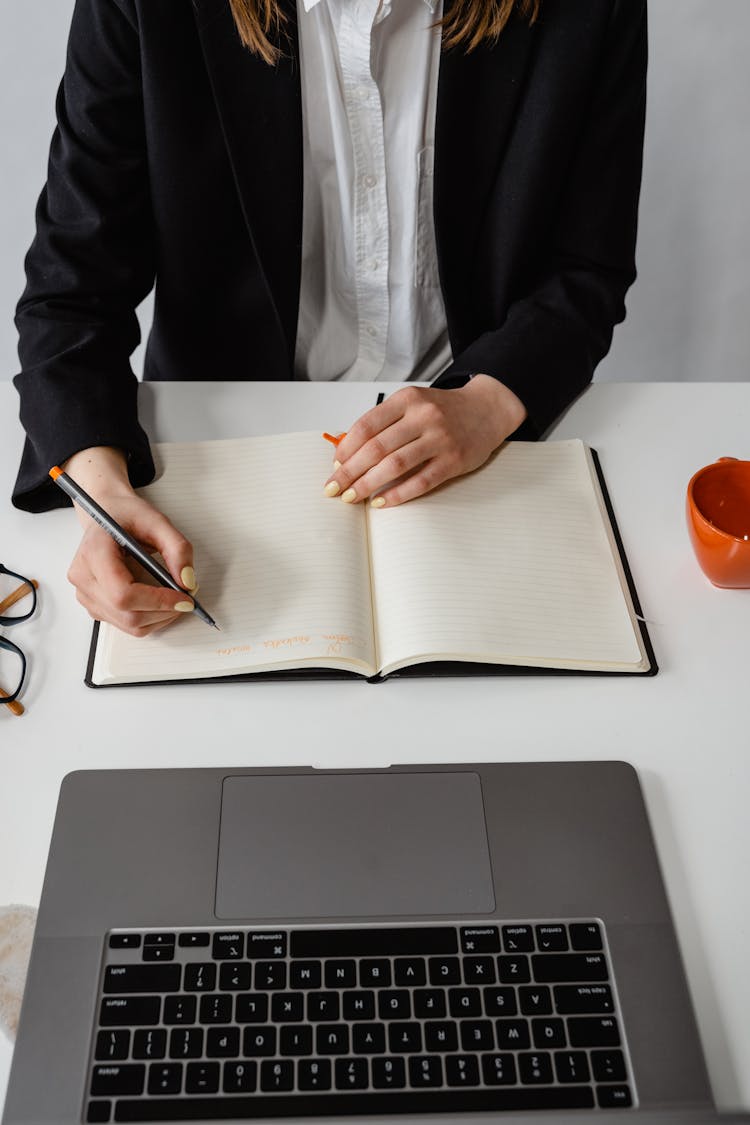 A Person Writing On A Planner