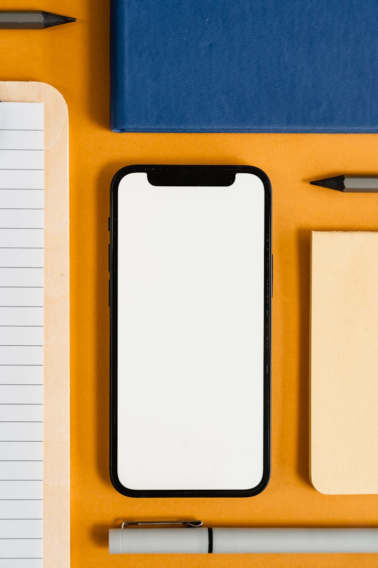 A Flatlay Of A Smartphone And Office Supplies