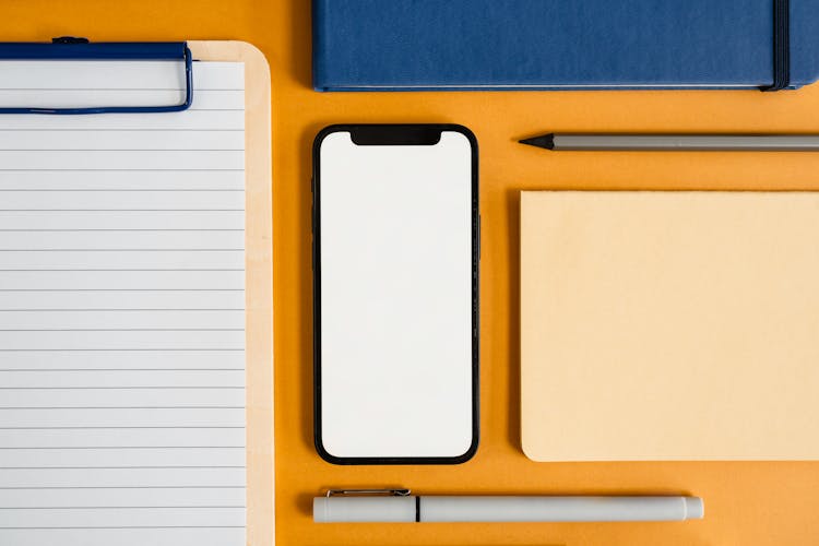 A Flatlay Of A Smartphone And Office Supplies