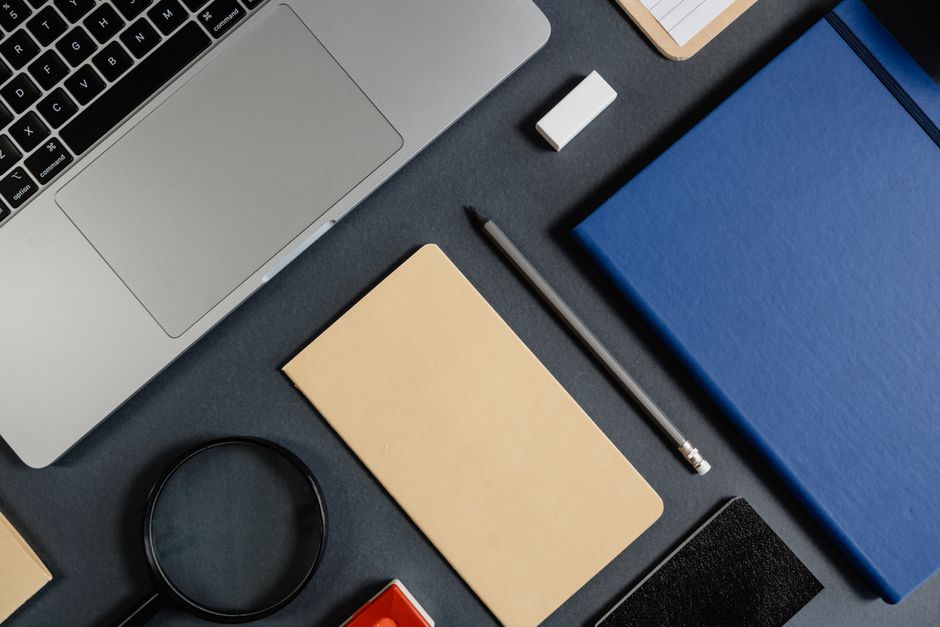 Minimalist workspace featuring a laptop, notebooks, pencils, and stationery in a flat lay design.