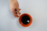 Person Holding Orange Ceramic Mug