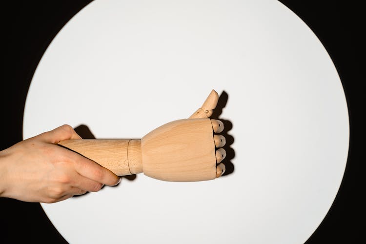 Person Holding A Wooden Hand With Thumbs-Up Gesture