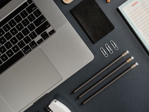 Free Top view of a laptop, pencils, notepad, and stationery arranged on a black surface, perfect for work themes. Stock Photo