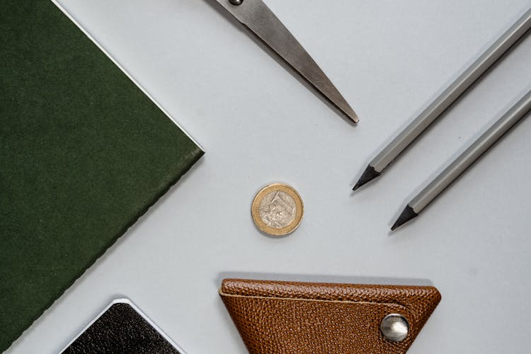 Stationery Items And A Coin Lying On A Table