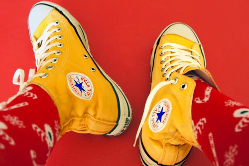 Free Close-up of yellow Converse sneakers paired with red socks on a red background. Stock Photo