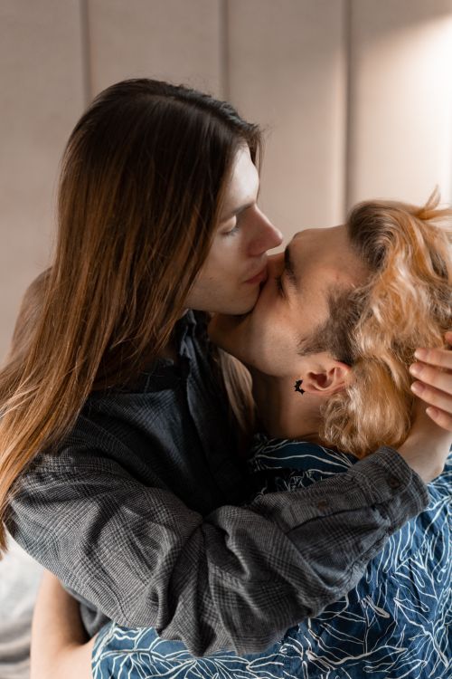 Free A tender moment of affection between two men embracing and kissing indoors. Stock Photo