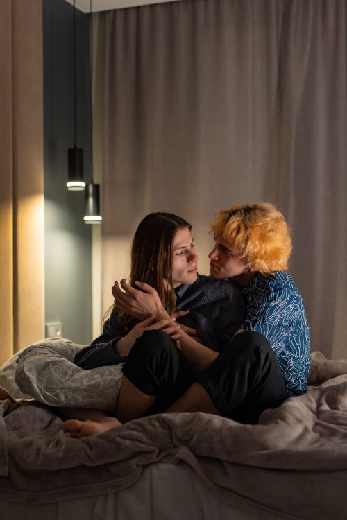 Free A warm and intimate moment of a couple embracing on a bed in a cozy bedroom atmosphere. Stock Photo