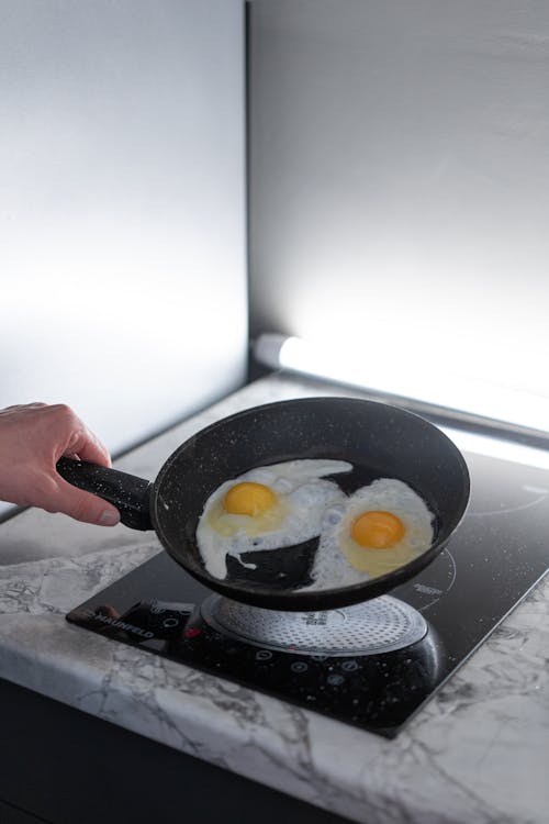 Free A Person Holding a Pan with Cooked Eggs Stock Photo