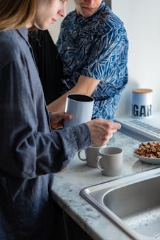 Two adults making coffee in a modern kitchen setting.