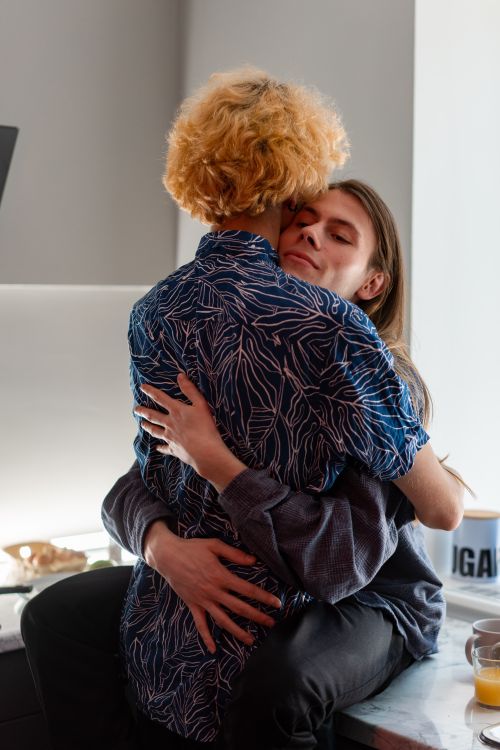 Free A couple shares a warm embrace in a cozy, modern kitchen. Stock Photo