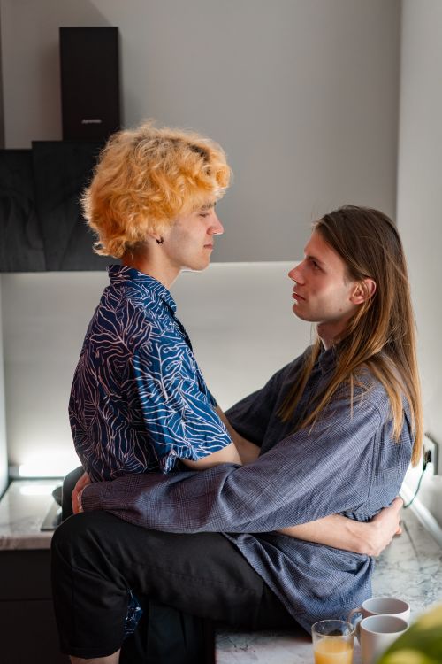 Free A loving couple embracing in a brightly lit modern kitchen, embodying warmth and connection. Stock Photo