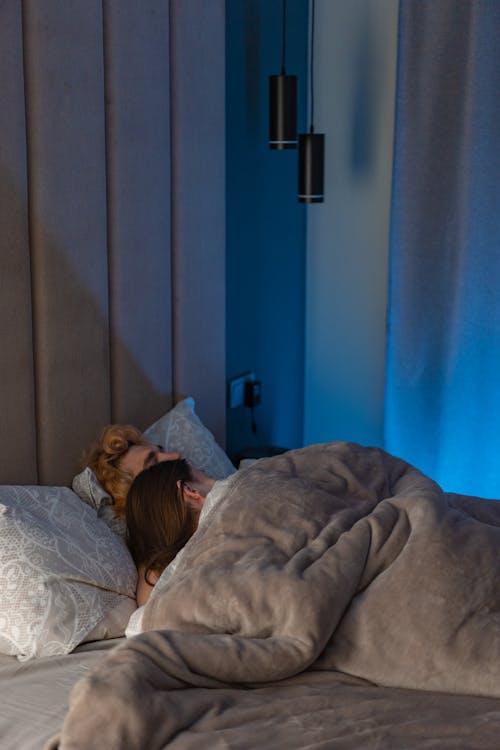 Женщина, лежащая на кровати, покрытой одеялом