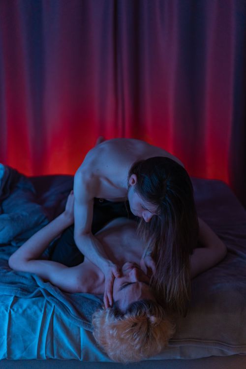 Free A tender and intimate moment between a couple embracing on a bed in dim lighting. Stock Photo