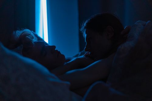 Free A romantic moment of two men sleeping closely together under soft blue lighting, conveying warmth and affection. Stock Photo