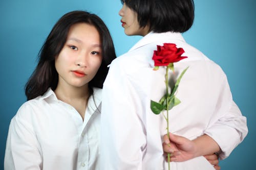 Asian women in white shirt with bright red blooming rose