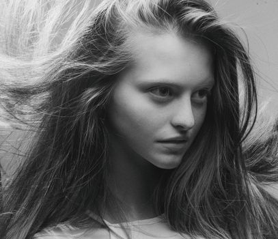 Elegant black and white portrait of a woman with windblown hair, conveying grace and movement.