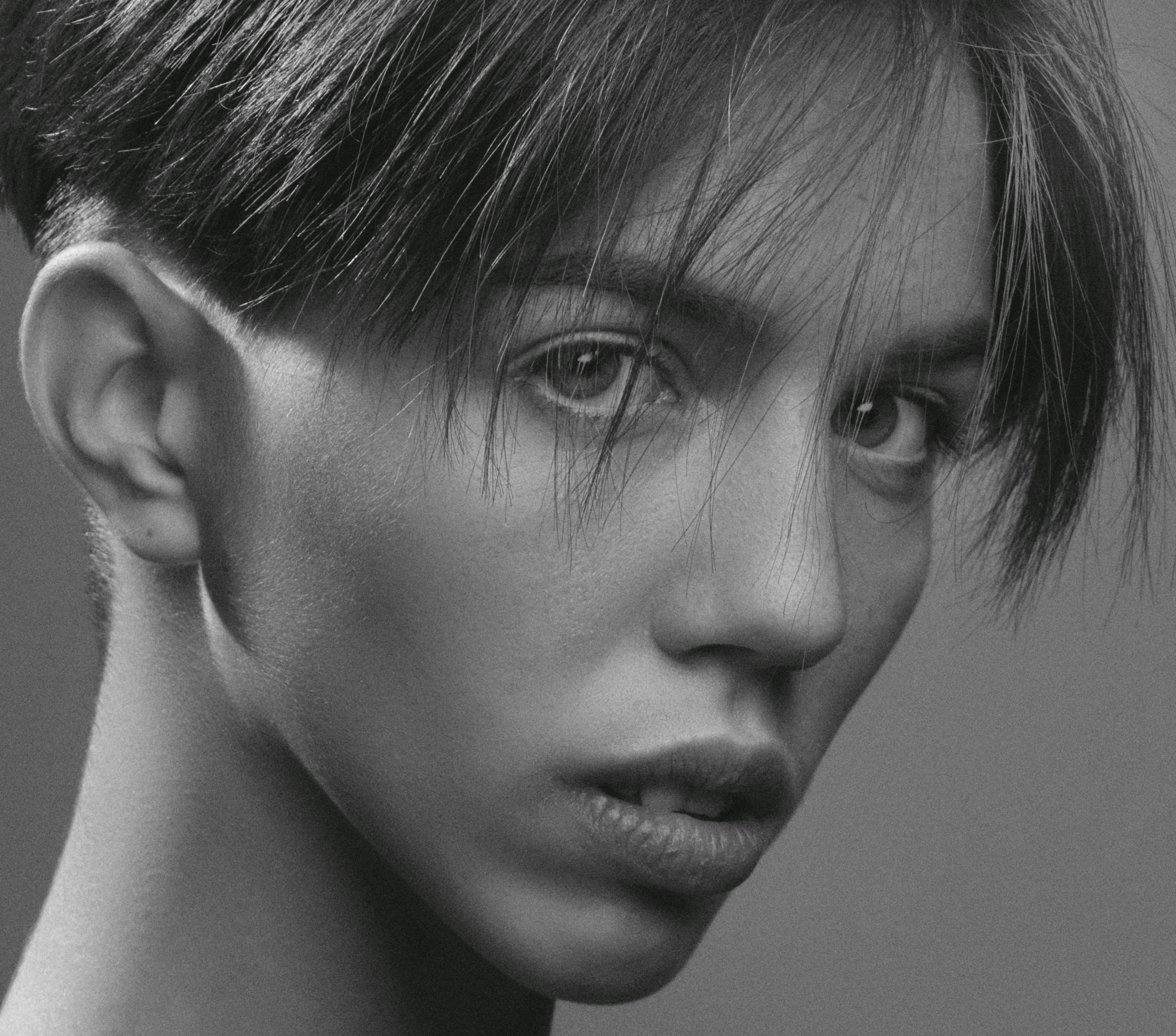 Monochrome close-up portrait capturing a young person's expressive gaze.