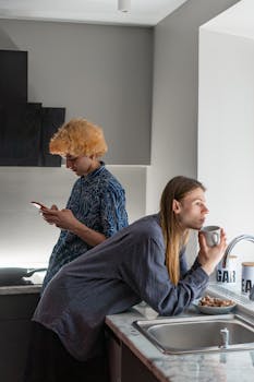 Two people relaxing in a modern kitchen, enjoying their morning routine.