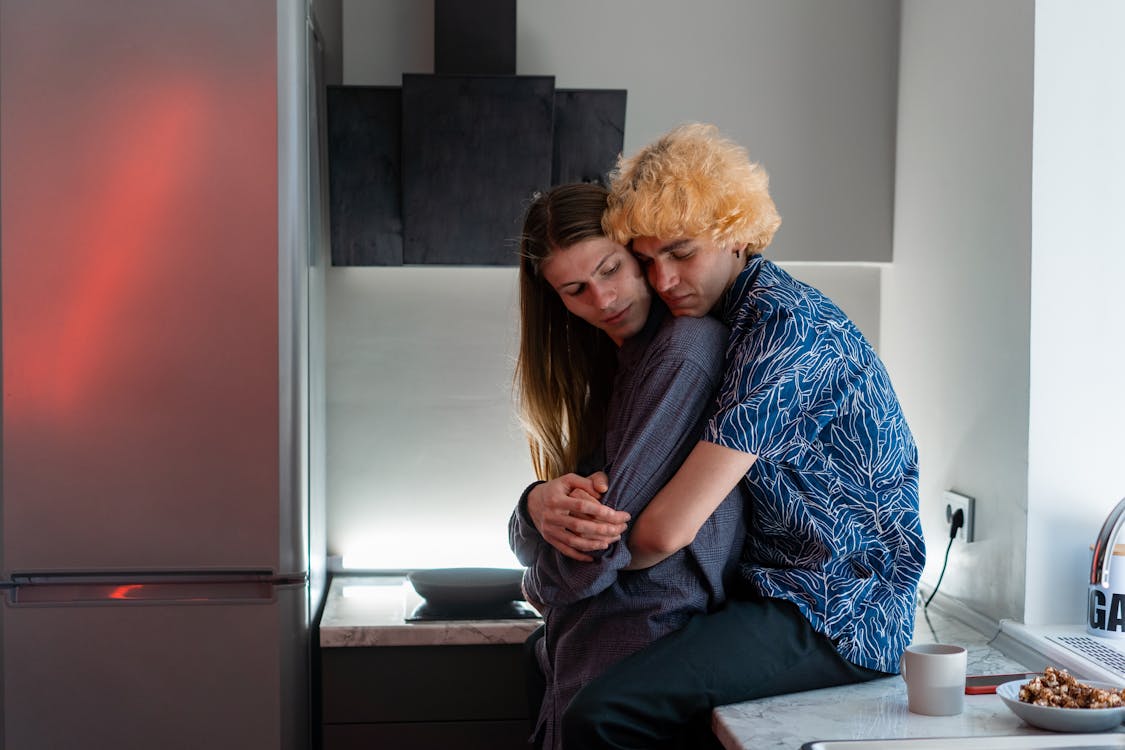man sitting on kitchen counter hugging woman