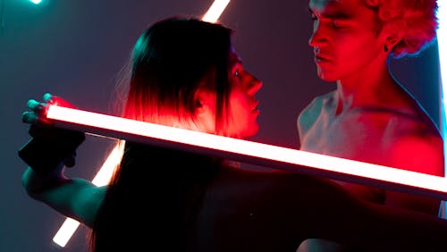 Free A Couple Looking at each other while Holding Neon Light Stock Photo