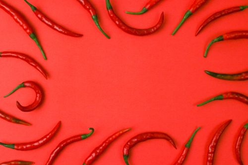 Free Vibrant red chili peppers arranged on a red background creating a spicy visual. Stock Photo