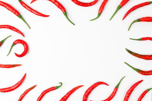 Free A vibrant arrangement of red chili peppers on a white background, perfect for food-oriented projects. Stock Photo