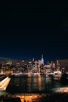 Stunning night view of the illuminated New York City skyline reflecting on the water.