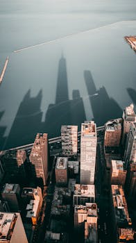Stunning aerial view of Chicago showcasing towering skyscrapers and their shadows on a calm body of water.