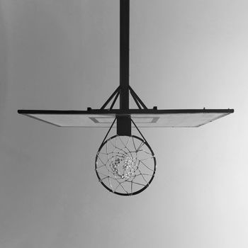 A black and white photo of a basketball hoop captured from beneath, emphasizing the net.