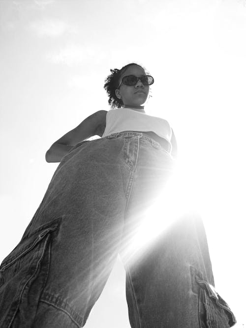 Free Grayscale Photo of a Woman with Sunglasses Wearing Denim Jeans Stock Photo