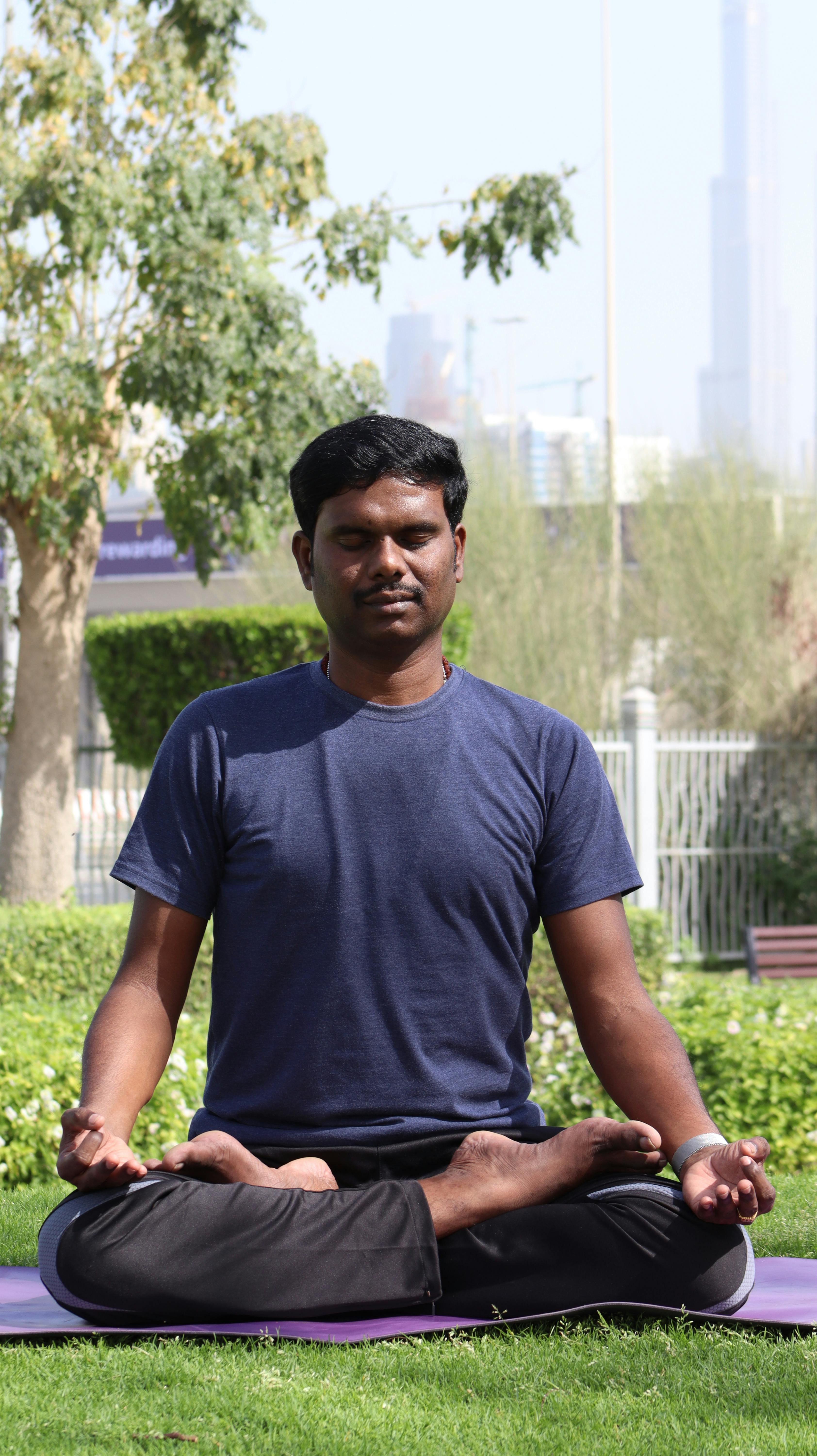 Photo of a Man in a Blue Shirt Meditating with His Eyes Closed
