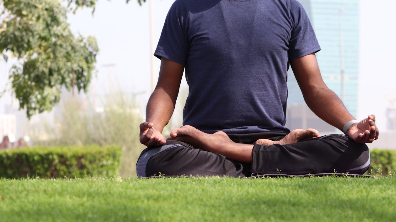 Free Man Sitting on Grass While Doing Yoga Stock Photo