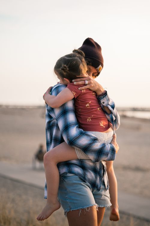 Free A mother holds her daughter in an affectionate embrace on a Michigan beach at sunset. Stock Photo