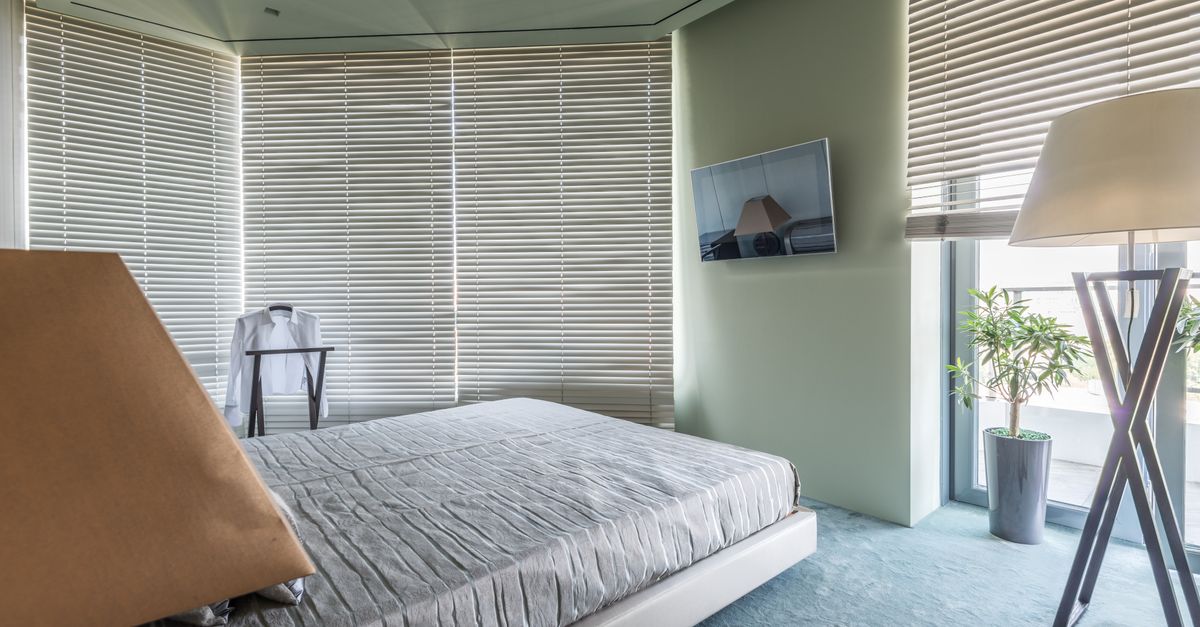 Tidy minimalist bedroom with made bed, clear surfaces and open blinds