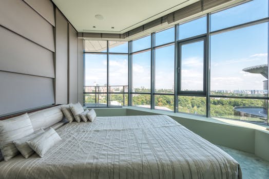 Luxurious bedroom featuring large windows and a panoramic city view.
