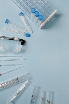 A collection of lab equipment including test tubes and goggles on a blue surface.