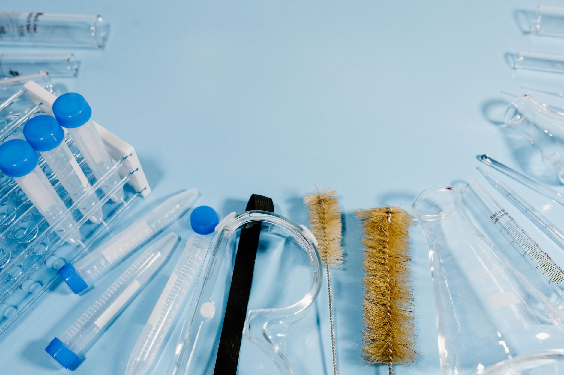 Variety of laboratory glassware and cleaning brushes on a blue surface.