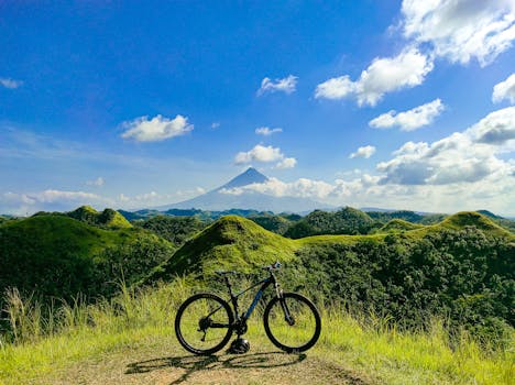 Bicycle parked on grassy hill with scenic view of mountains and clear blue sky.