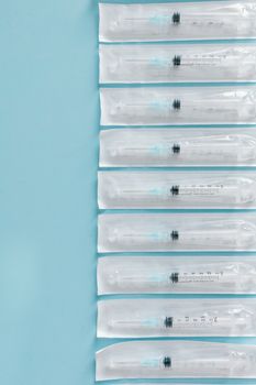 Top view of sterile syringes arranged vertically on a blue background.