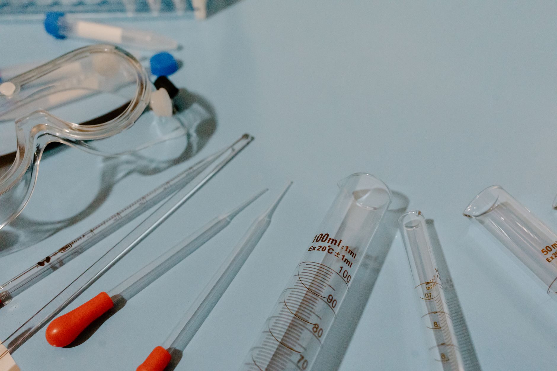 Detailed view of lab equipment like test tubes and goggles on a blue surface.